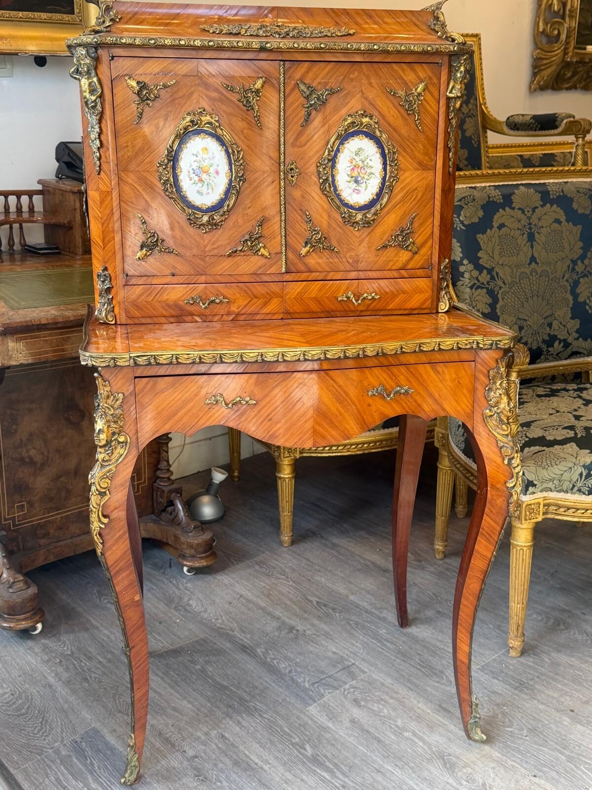 Bonheur du jour en placage de bois précieux, gradin à deux portes ornées de médaillons de porcelaine bleue à fleurs, bronzes dorés aux angles et pieds cambrés