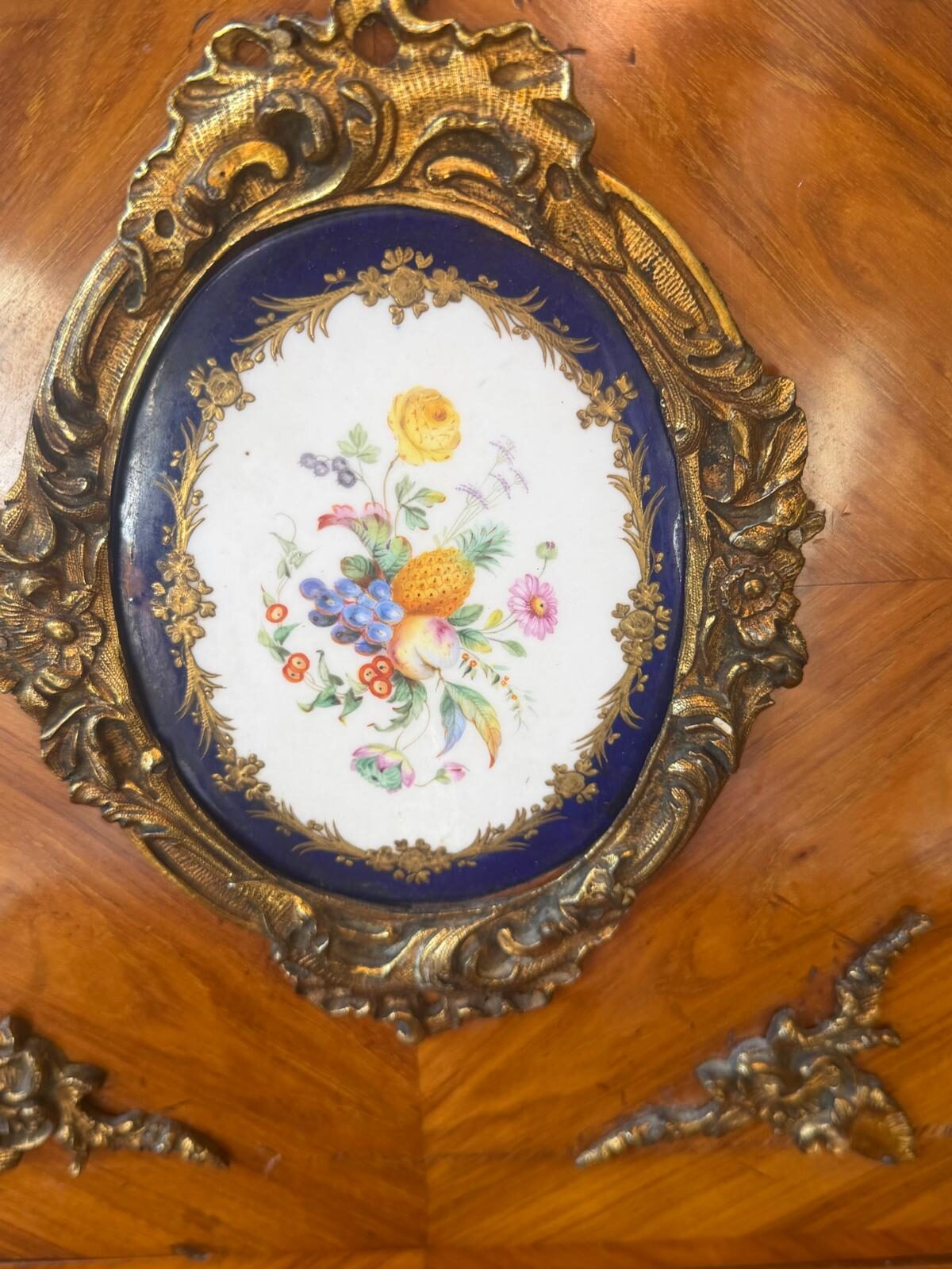 Médaillon ovale en porcelaine à fond bleu, bouquet de fleurs et de fruits peint à la main, cadre de bronze doré à décor rocaille