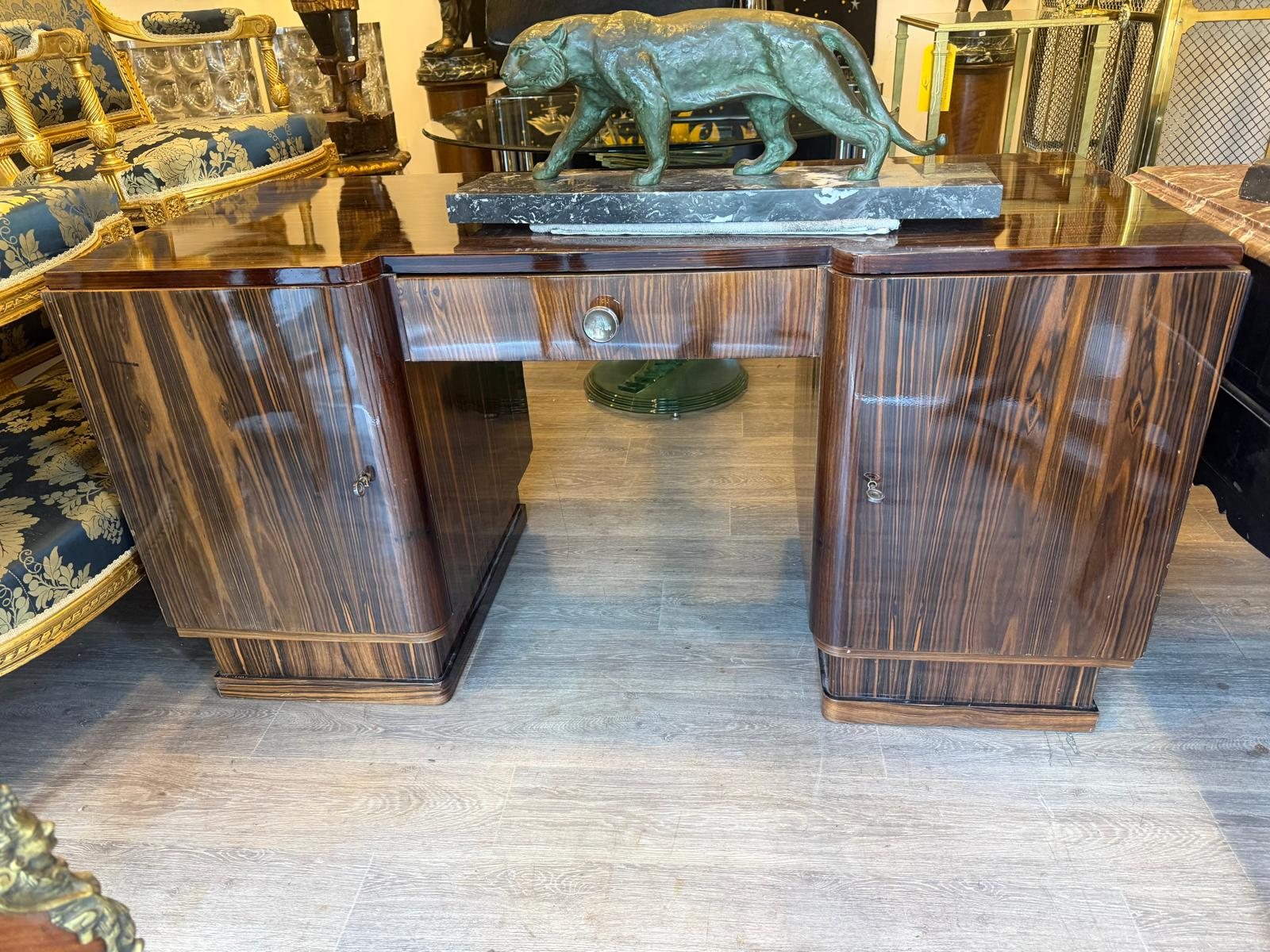 Bureau Art déco à double caisson plaqué d'ébène de Macassar, une panthère en bronze posée sur le plateau, dans la galerie