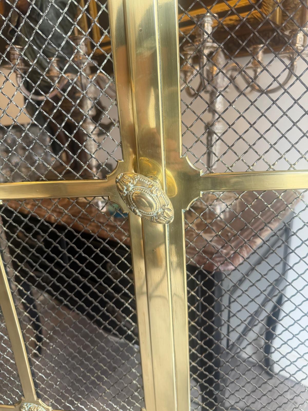 Bouton ovale en laiton ciselé à perles, fixé sur le montant central entre deux panneaux de grillage losangé