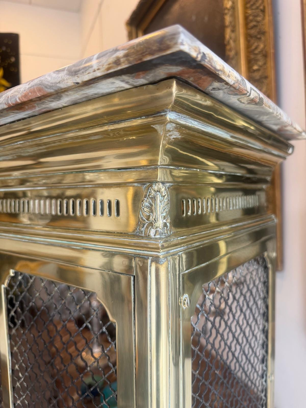 Angle supérieur du meuble : tablette de marbre brèche débordante, frise ajourée de fentes verticales et agrafe d'acanthe appliquée au coin