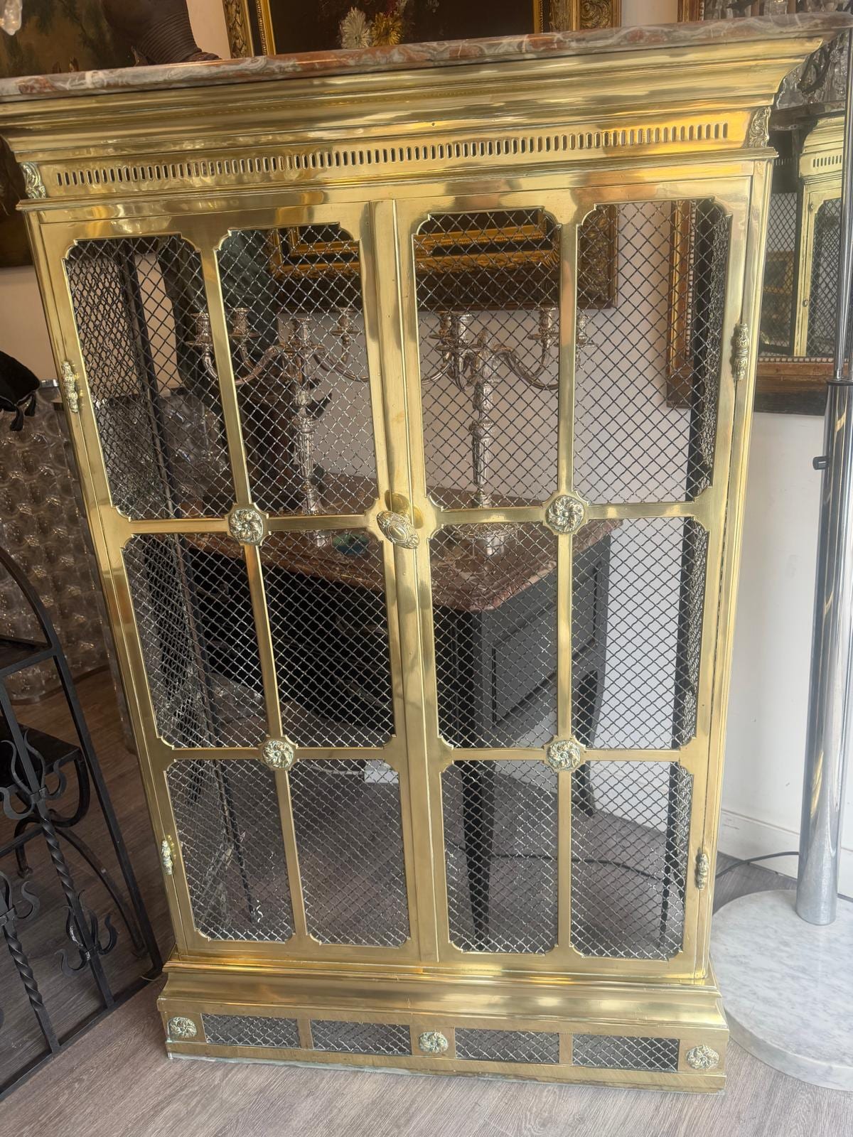 Cache-radiateur en laiton doré à deux portes garnies de grillage losangé, dessus de marbre brèche et frise ajourée, dans une galerie d'antiquités