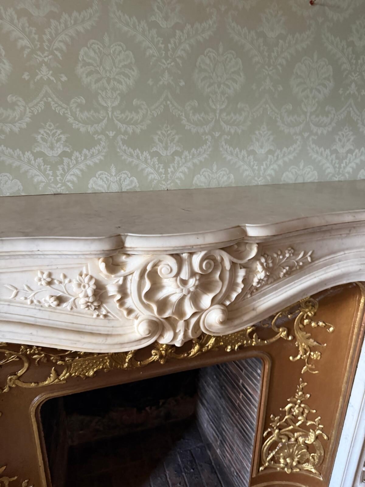 Motif central du linteau : coquille rocaille encadrée de feuilles d'acanthe et de fleurettes sculptées dans le marbre blanc