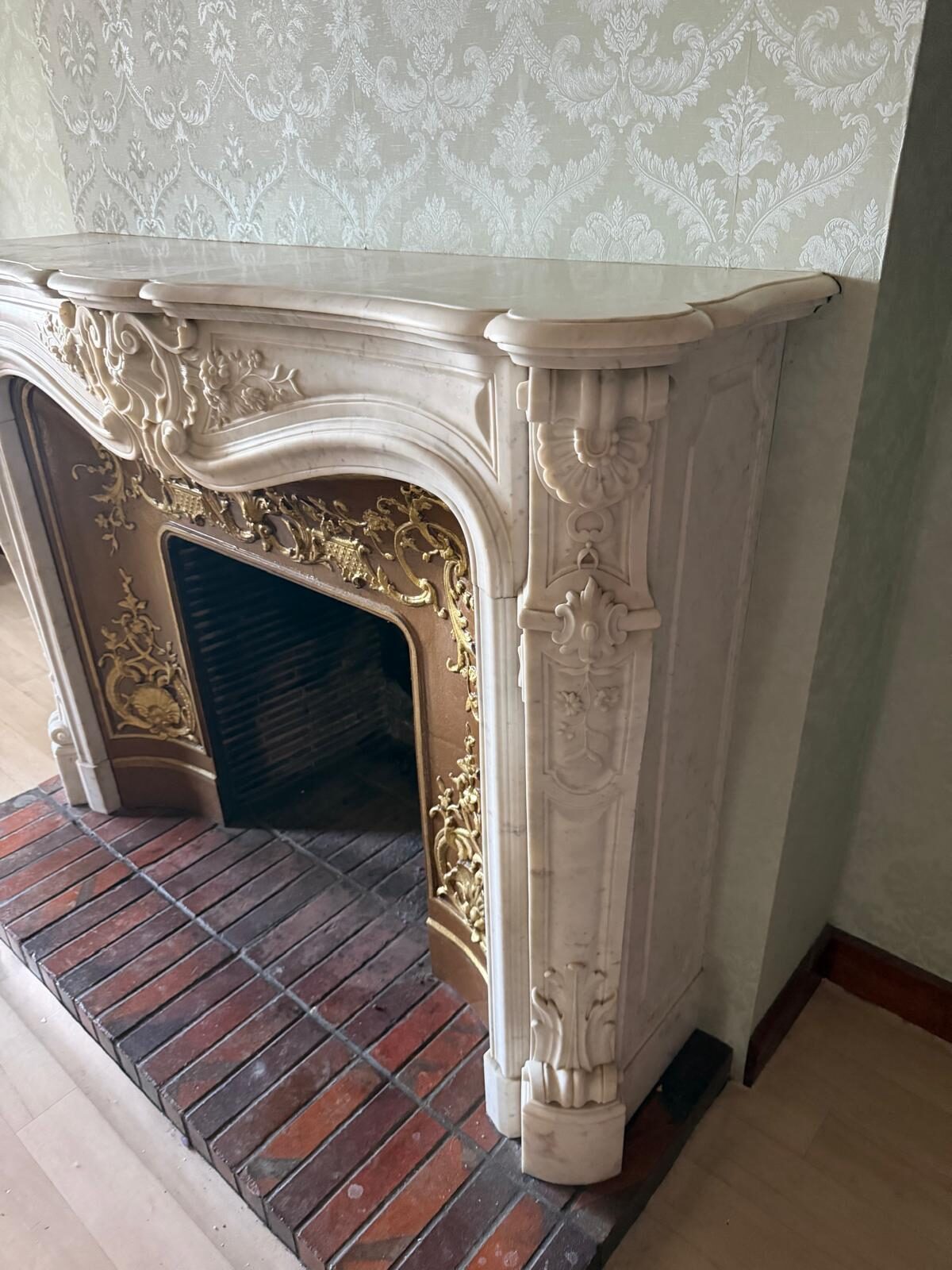Vue de trois quarts : jambage sculpté d'une coquille et de feuillages, tablette moulurée en doucine et intérieur à décor doré