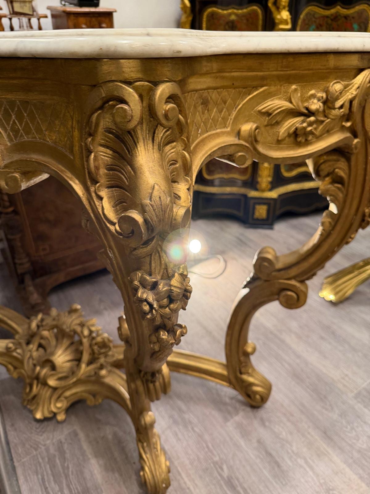 Détail d'un pied cambré en bois doré, sculpté de feuillages et terminé en enroulement