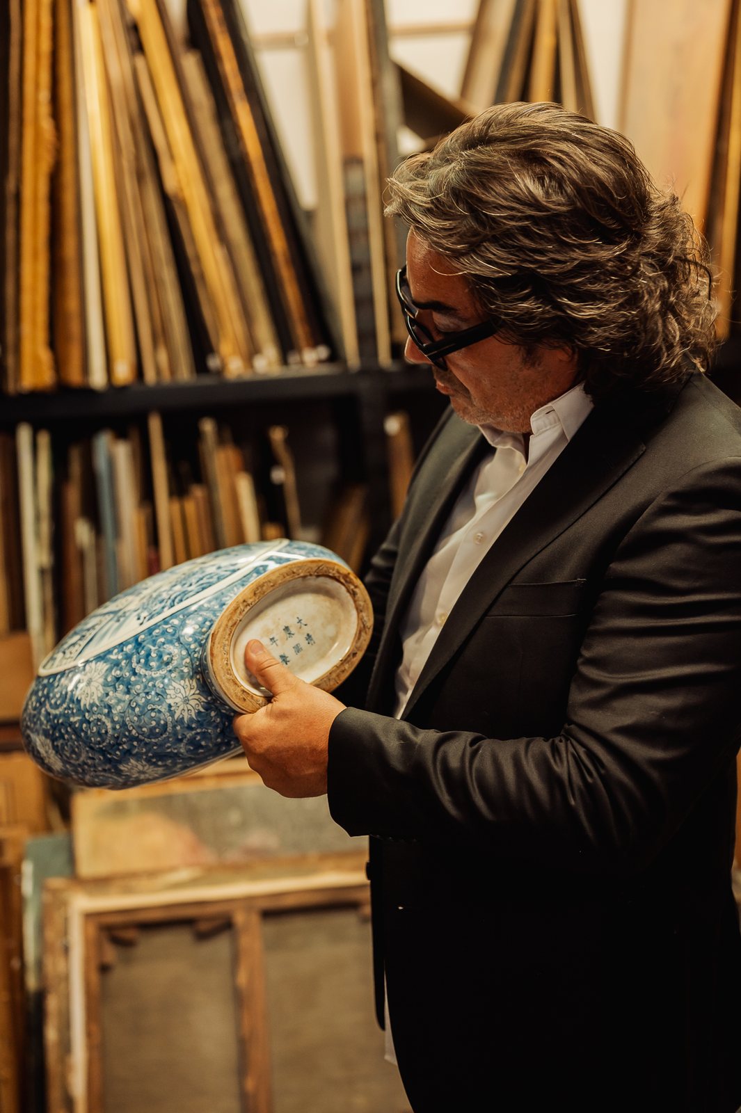 Éric retourne la gourde en porcelaine bleu et blanc pour lire la marque sous la base