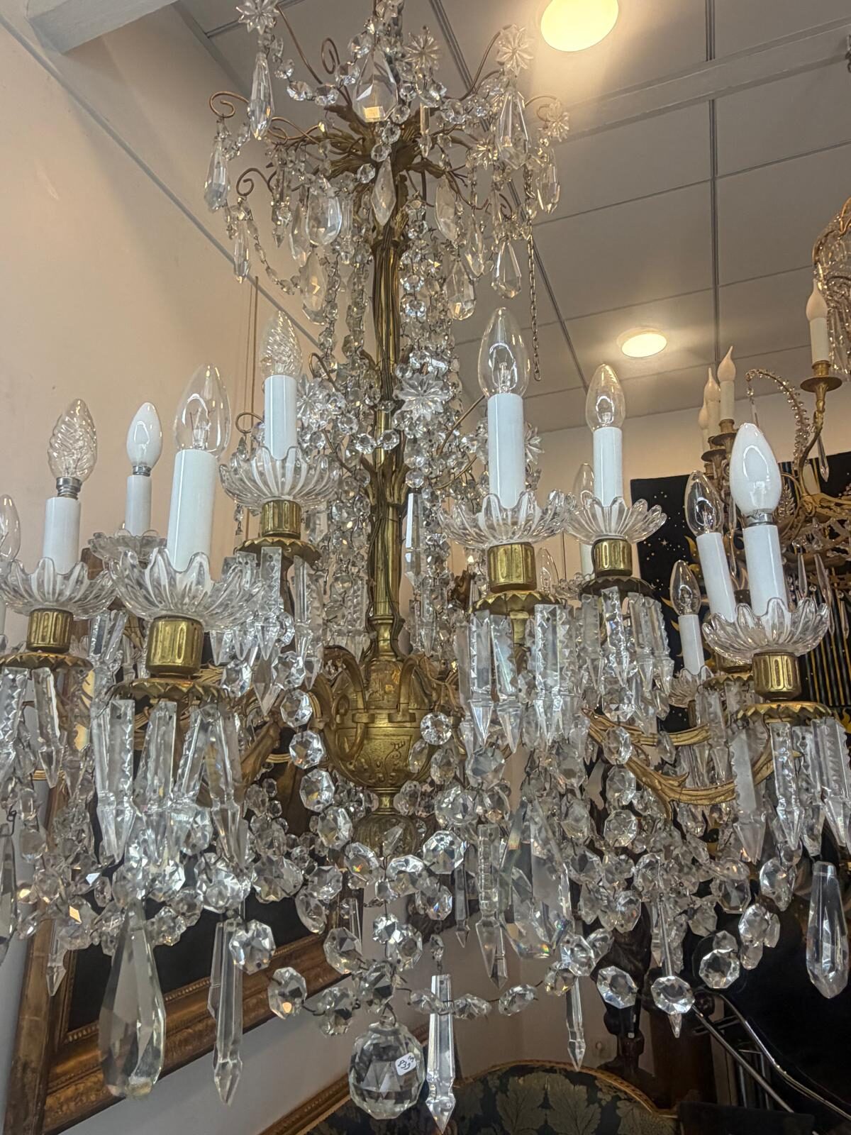 Grand lustre à pampilles de cristal taillé et monture en bronze doré, deux rangs de bras de lumière, suspendu dans la galerie