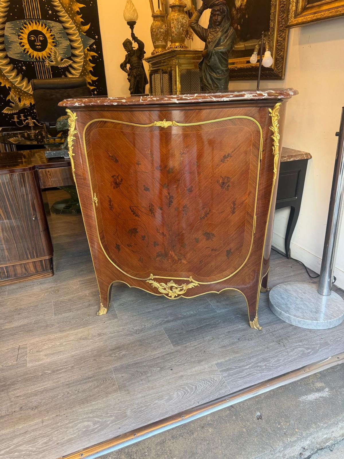 Meuble d'appui de style Louis XV à façade galbée, marqueterie de fleurs, bronzes dorés et dessus de marbre rouge, dans la galerie