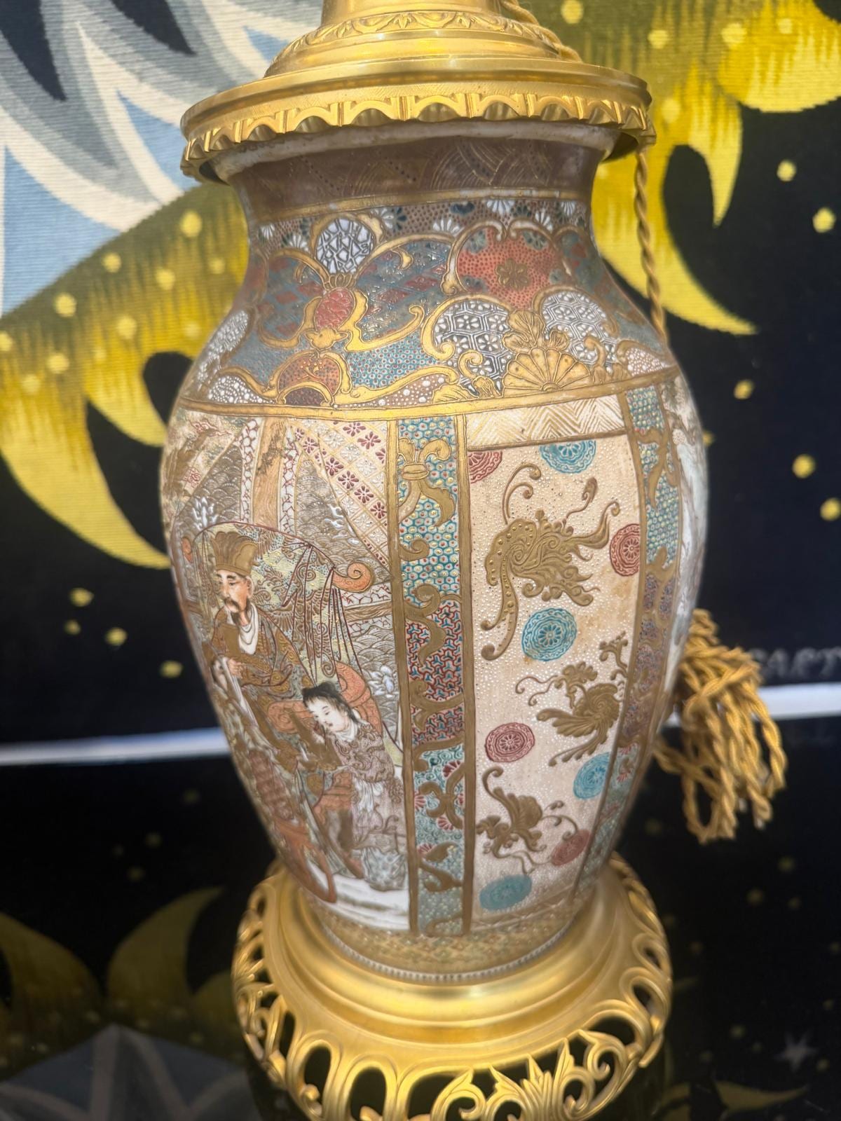 Gros plan sur une lampe : réserves peintes de personnages et d'animaux stylisés dans des médaillons, sur fond crème craquelé, base en bronze doré ajouré