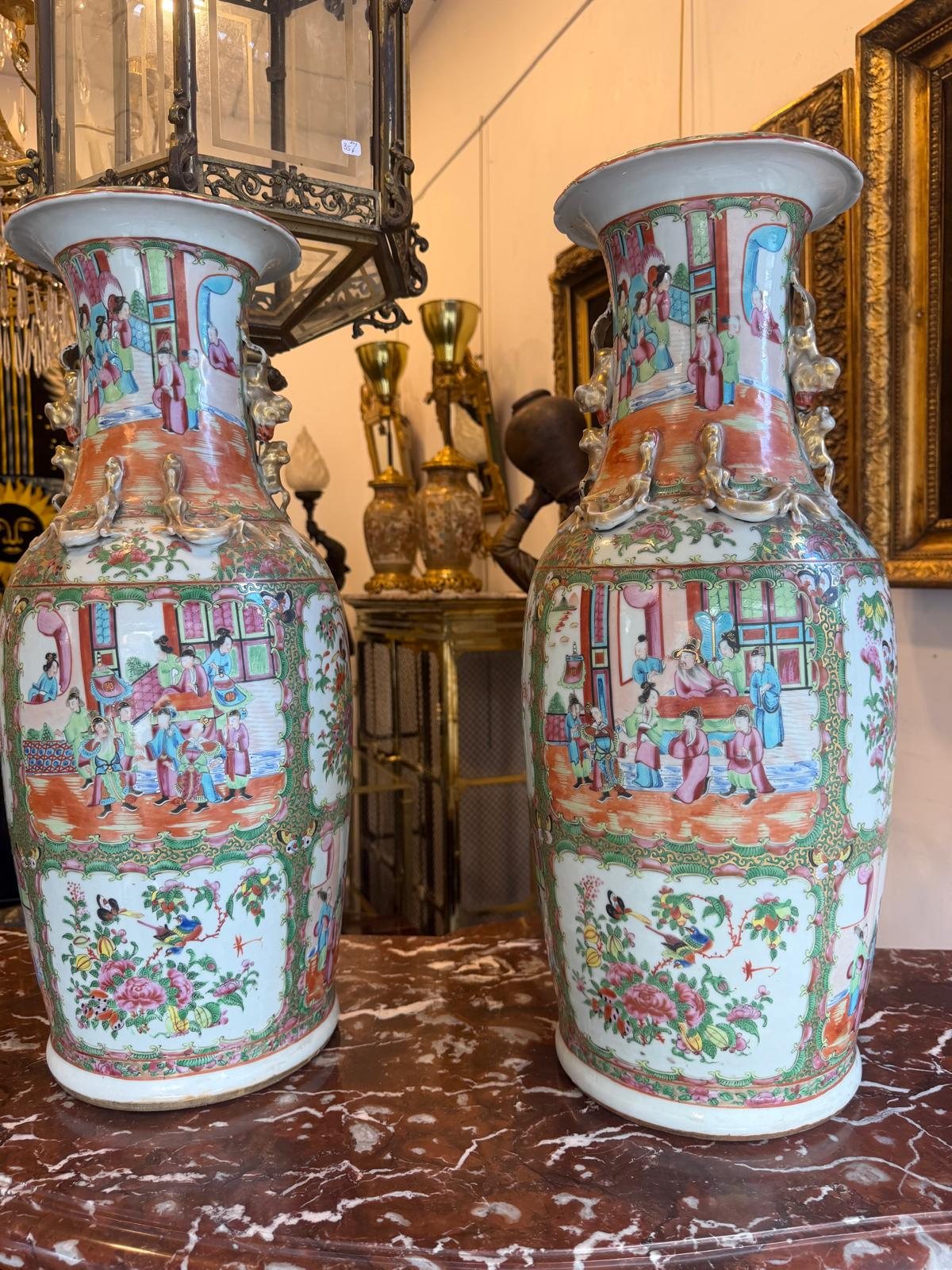 Paire de grands vases balustres en porcelaine de Canton à décor famille rose, posés sur une console de marbre rouge dans la galerie