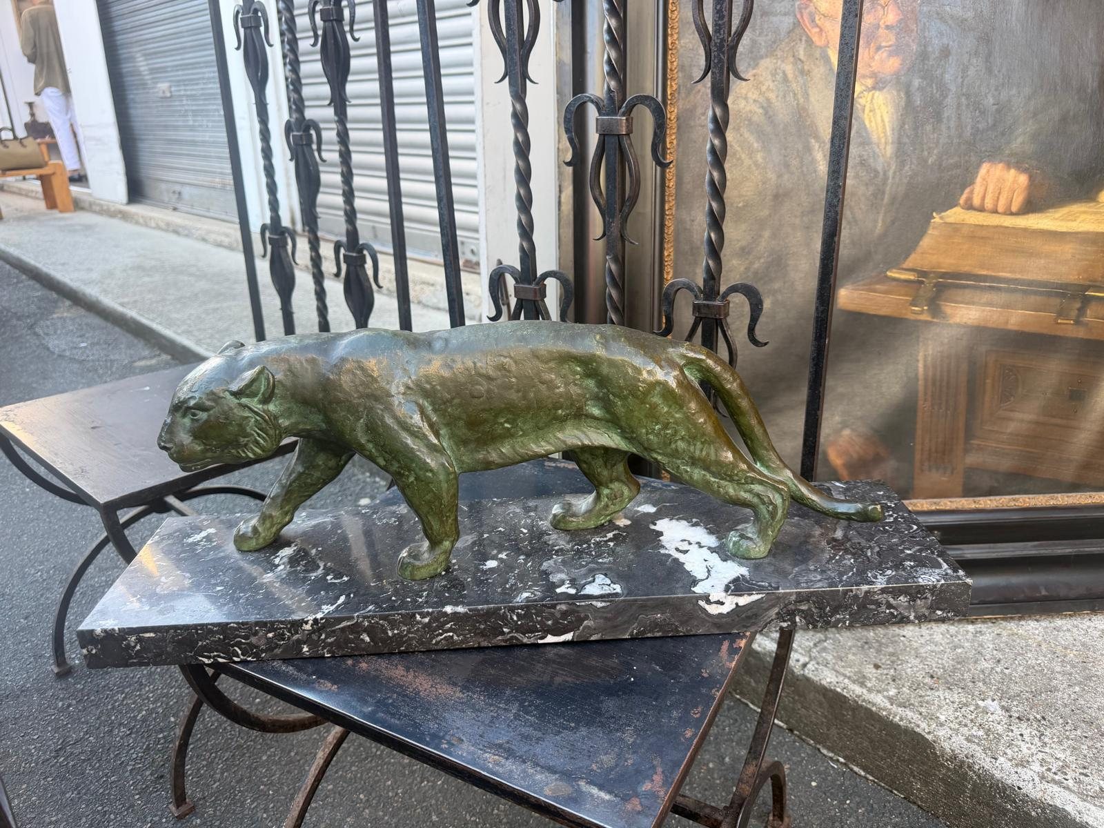 La panthère en bronze de profil en lumière du jour, échine en courbe continue de la nuque à la queue, socle de marbre veiné