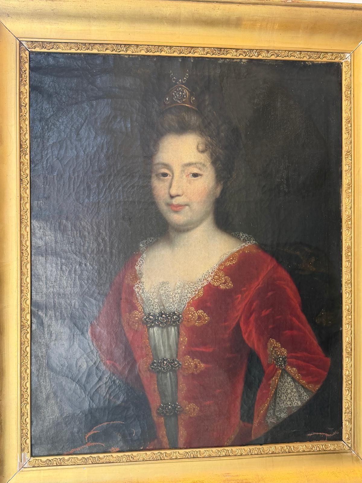 Portrait à l'huile d'une jeune femme en robe de velours rouge ornée de galons dorés, petite couronne dans les cheveux relevés, cadre en bois doré