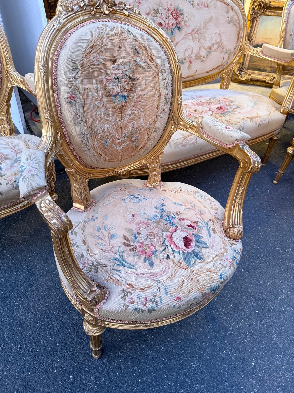 Fauteuil vu de trois quarts : accotoirs en bois doré, pieds fuselés et cannelés, tapisserie à fleurs