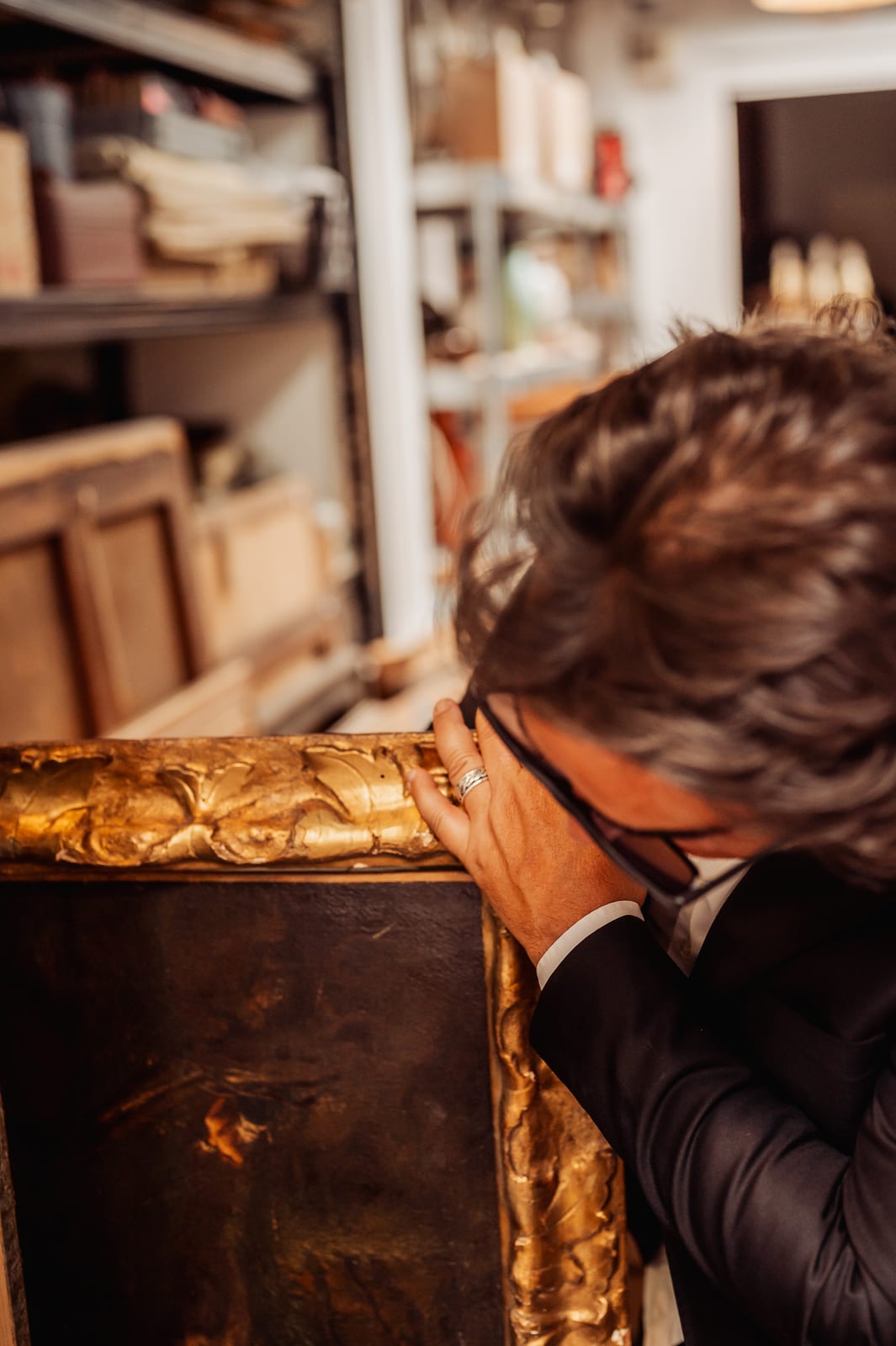Éric BENHAMOU examine de près le cadre doré sculpté de feuillages