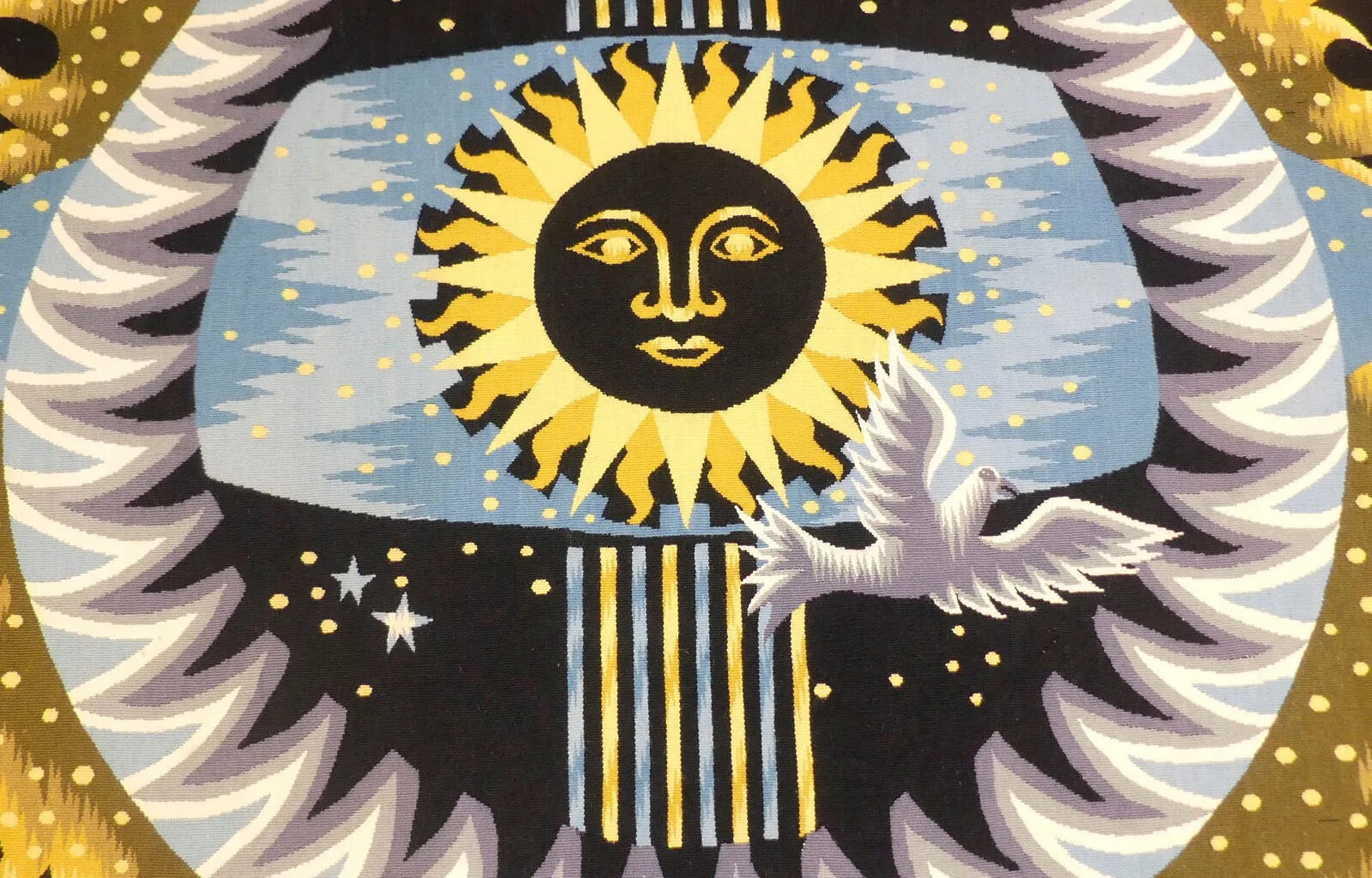 Centre de la tapisserie : disque solaire noir à visage souriant, couronne de rayons jaunes, ciel bleu piqué d'étoiles et colombe en vol