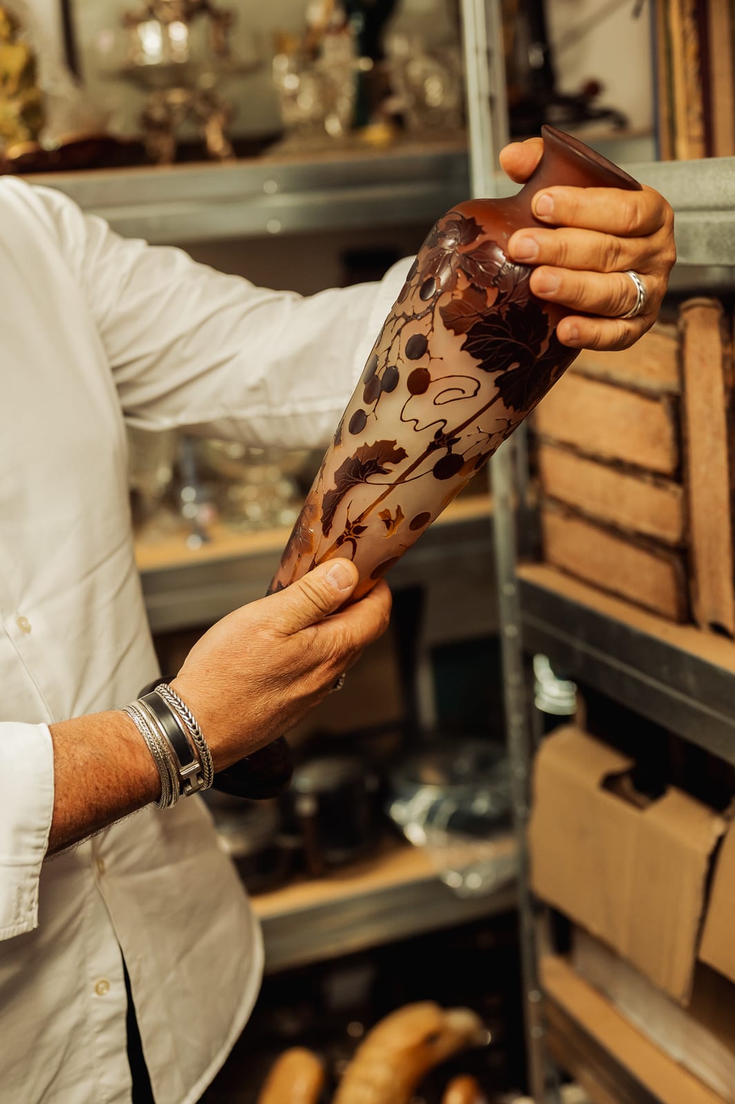 Le vase tenu à deux mains : décor gravé de baies et de feuillages bruns sur fond orangé